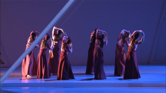 Dancers in long dark dresses on a blue stage