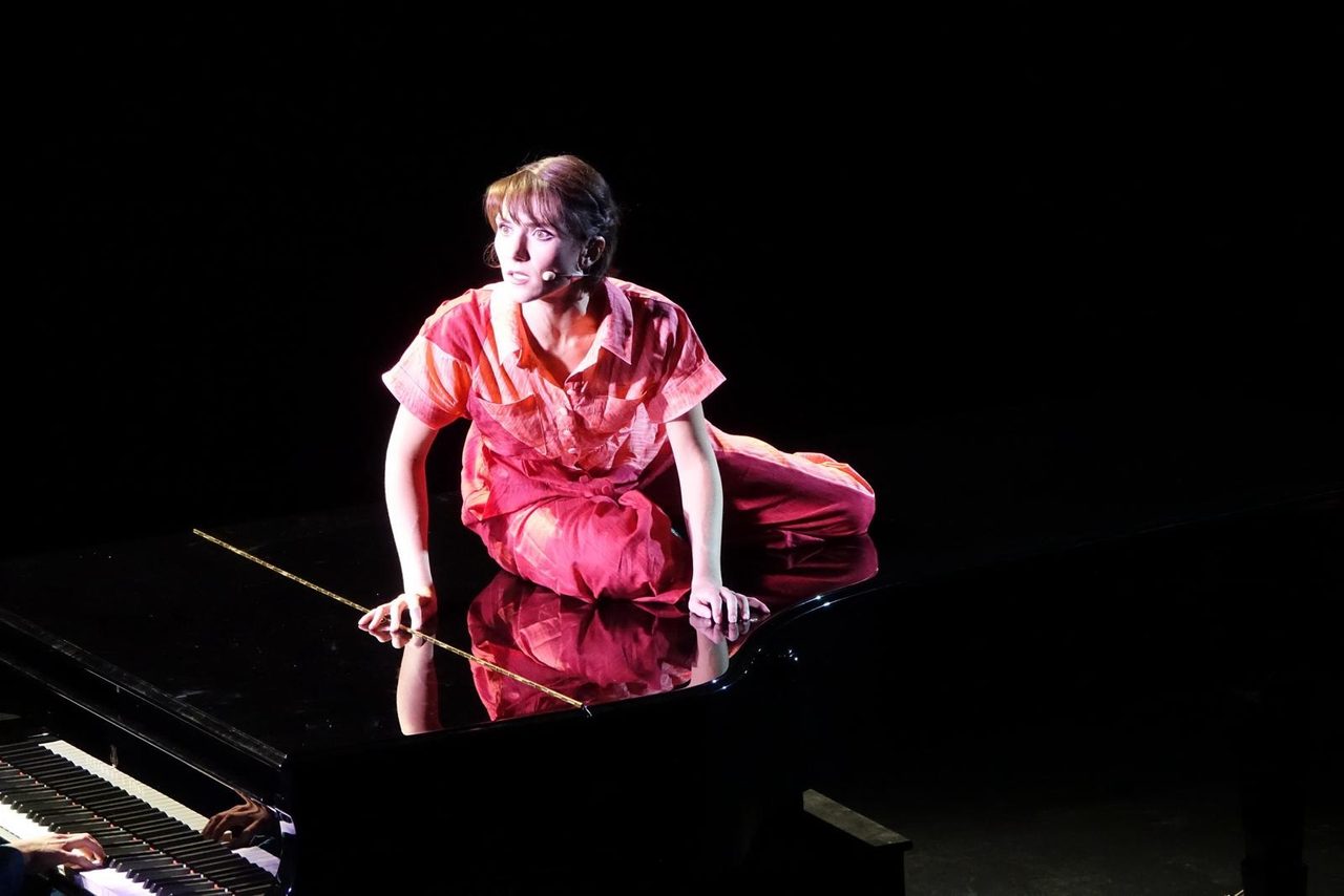 The actress in red kneeling on the piano