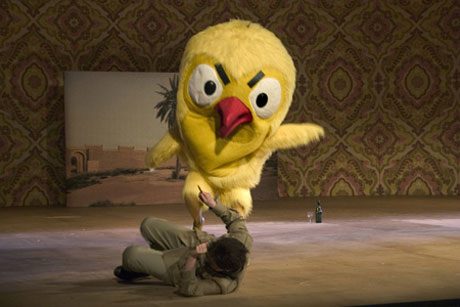 A giant yellow bird costume over a figure on the floor