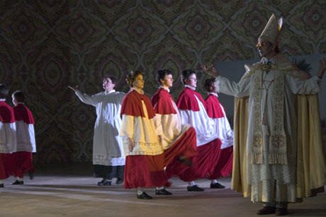 Choirboys in red and a bishop on stage