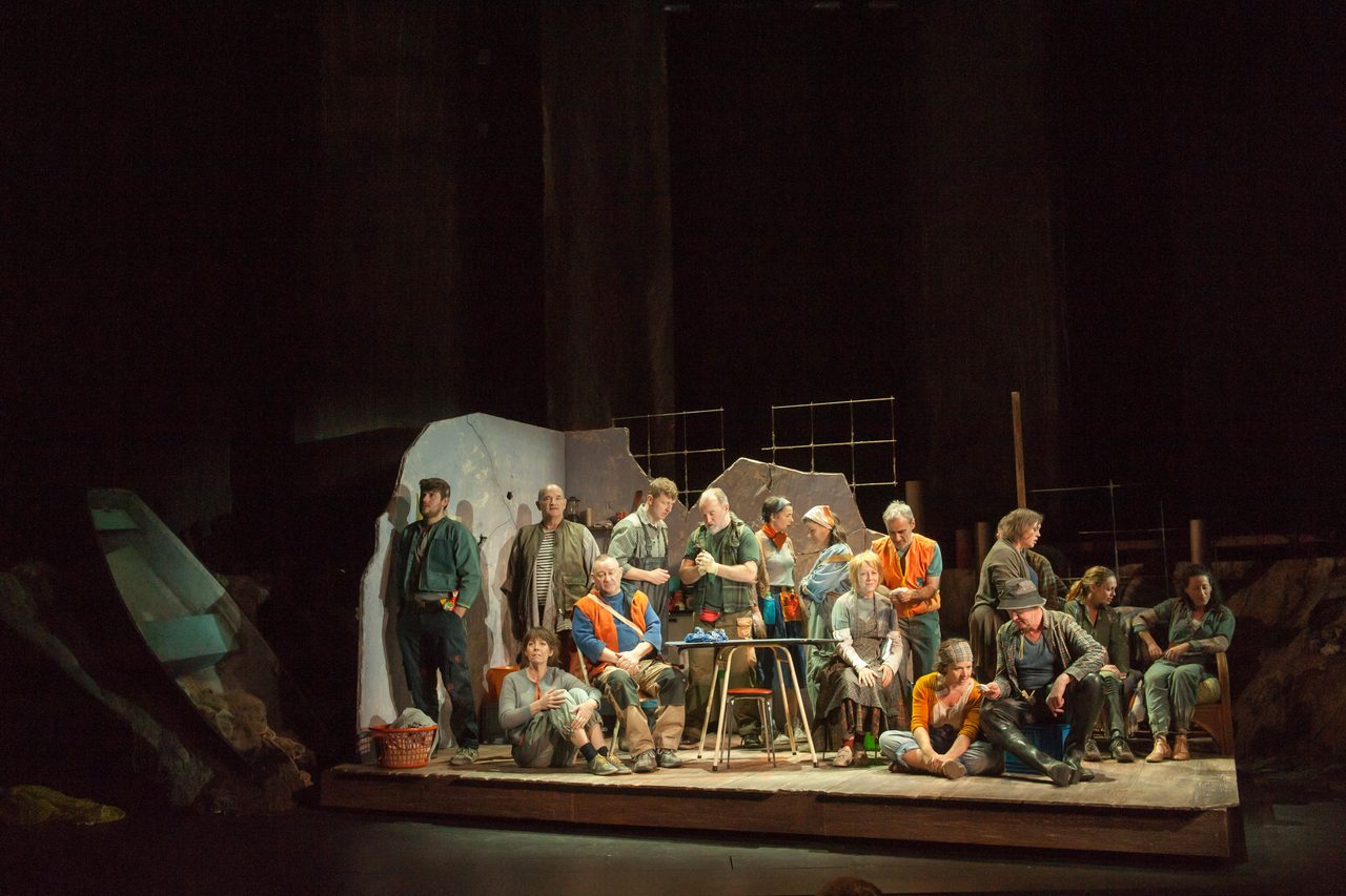 The ensemble gathered on a rock-like set