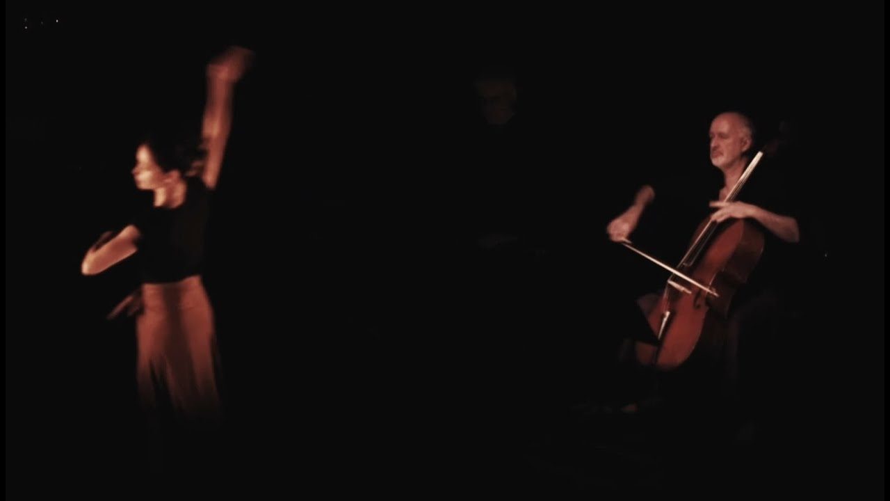 A dancer in a pool of light beside a cellist